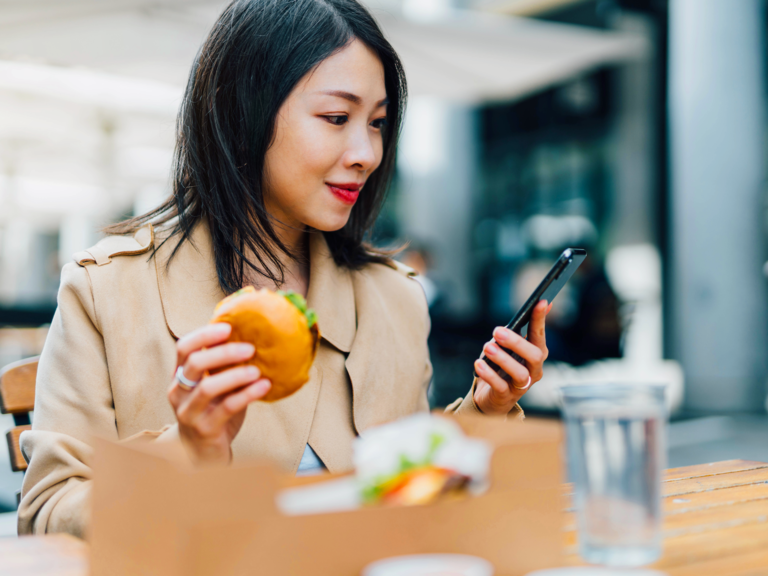 A woman uses an app to order additional items at a fast food restaurant.