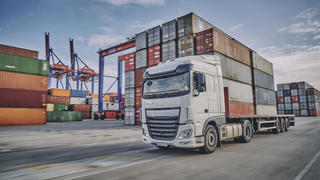 A semi truck driving through a busy port area.